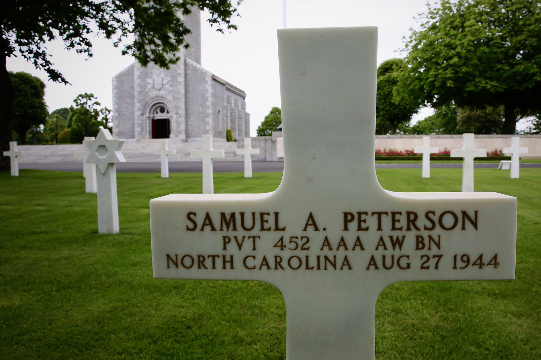 Chancy rubbed sand from Omaha Beach into the grave marker of Samuel Peterson, of Charlotte, in a custom that enables the name on the marker to stand out. Peterson is among several African American soldiers and sailors laid to rest at the Brittany American Cemetery.